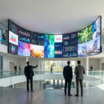Immersive curved LED wall displaying vibrant data and imagery in a bright, modern Poitiers commercial space with professionals.
